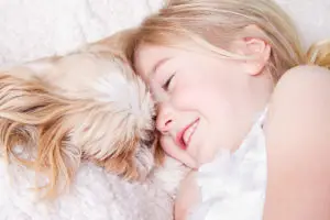 little girl in bed with her shih tzu
