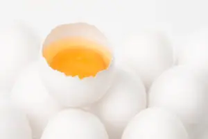 a raw egg cracked open sitting on other eggs