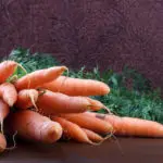 bunch of fresh carrots on rustic wooden table