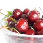 Fresh ripe cherries in a class bowl close-up isolated on white background.