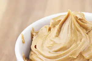 Creamy peanut butter in a dish with shallow depth of field.