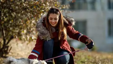 An attractive woman playing with her cute Shih Tzu dog at the park