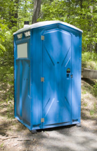 A blue porta potty located on the hiking trail