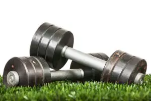 Iron dumbbell on green grass. Close up