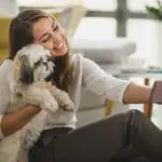 Shot of a cute young woman taking and selfie while relaxing with pet dog in her living room at the home.